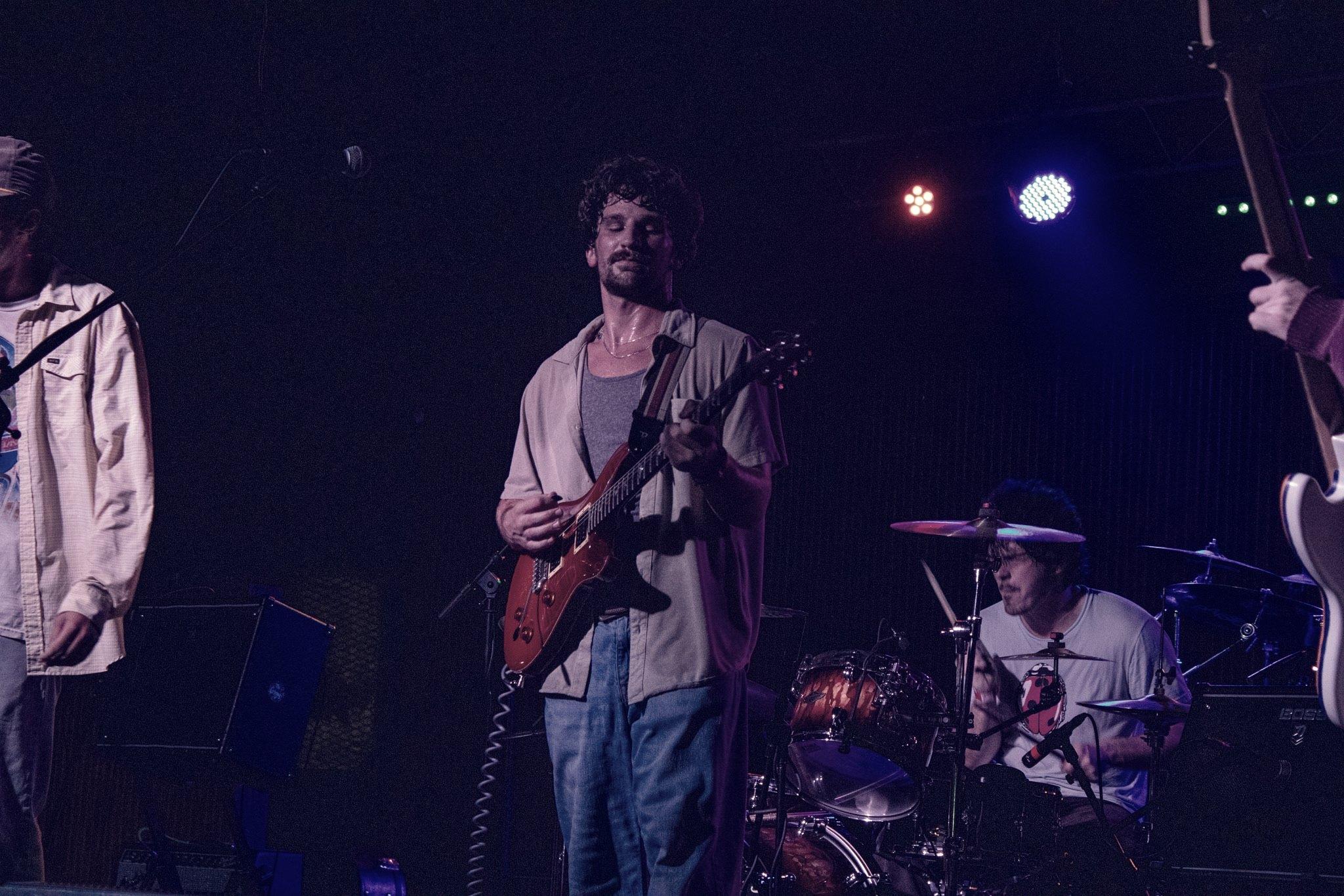 A band on a low stage in a timber-framed room, the floor packed to the walls.