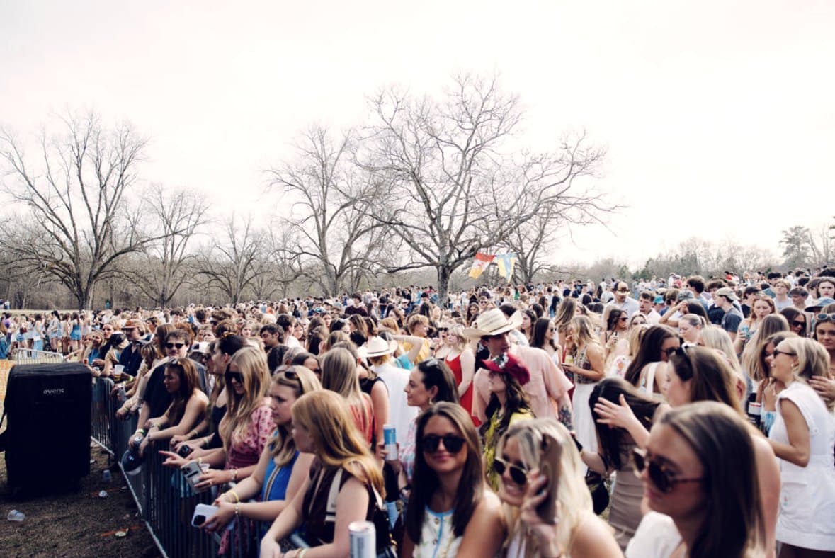 A daylight festival crowd filling a field under bare winter trees.