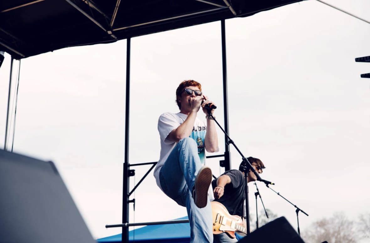 A singer photographed from below against an open sky at the front of the stage.