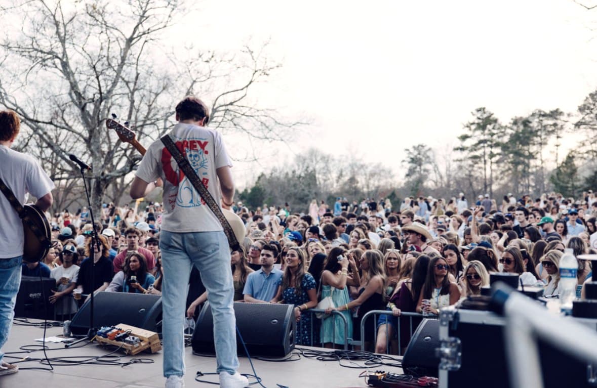 A guitarist at the front of the stage with the daylight crowd running back behind him.