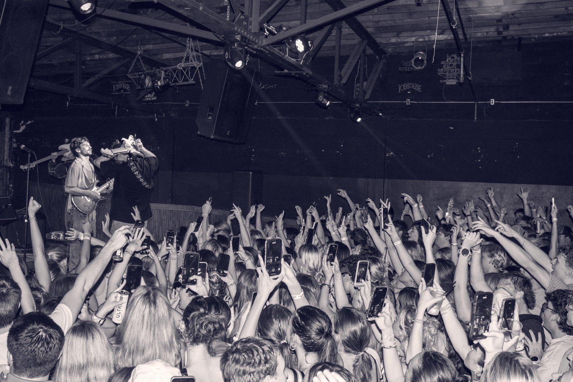 A room of raised hands photographed from the stage.